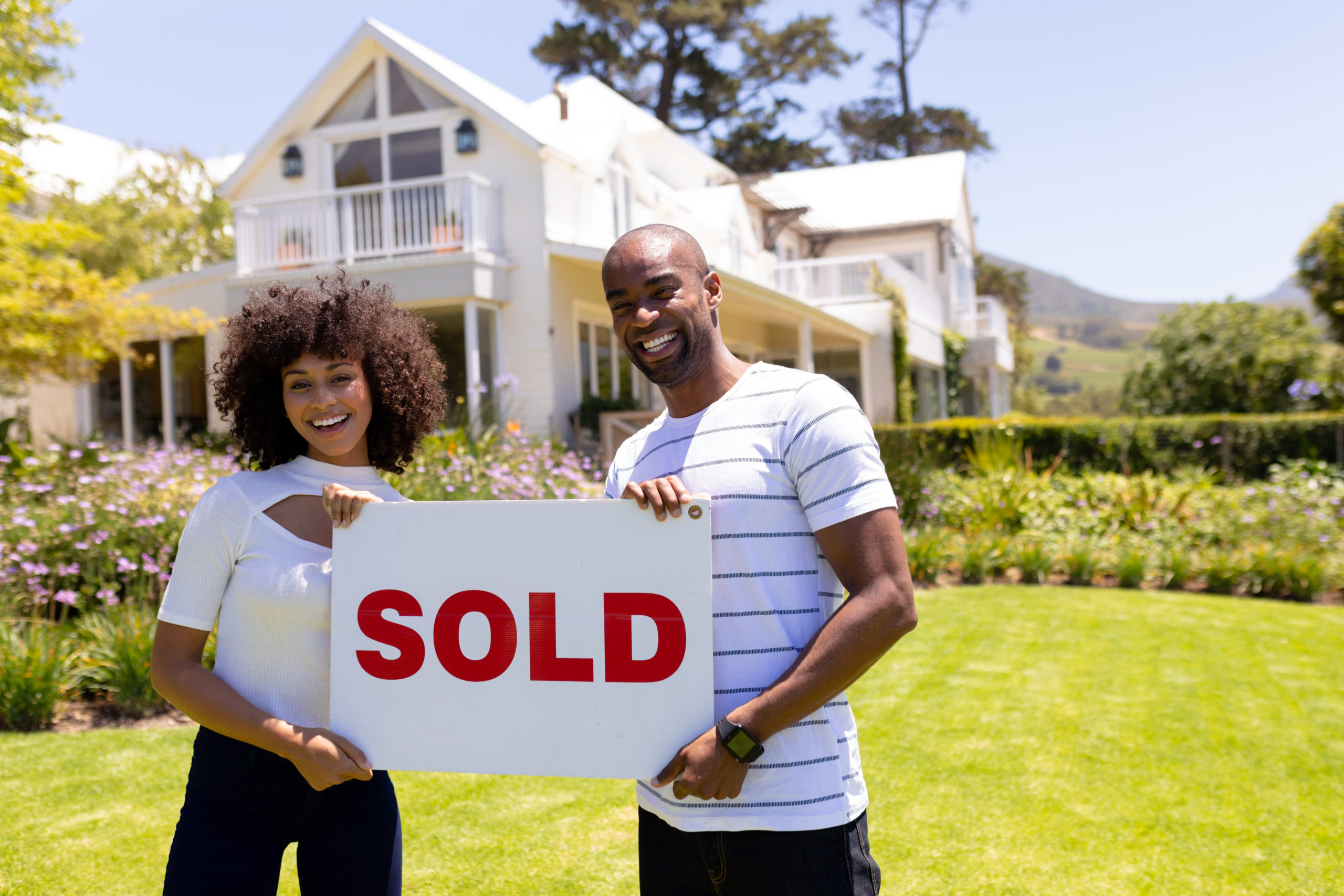 Couple holding a sold sign for a house