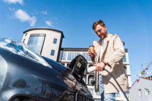 Man having a coffee while charging a Tesla electric vehicle