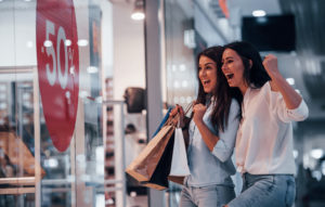 Two young women happily shopping at a black friday sale