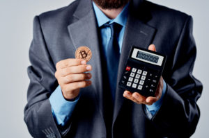 A man holding a bitcoin and calculator