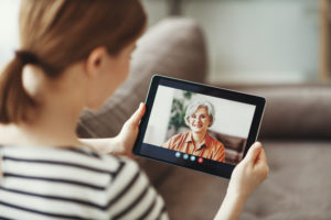 Young woman having video call with eldery mother on tablet