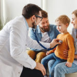 Doctor listening lungs of boy during family check up