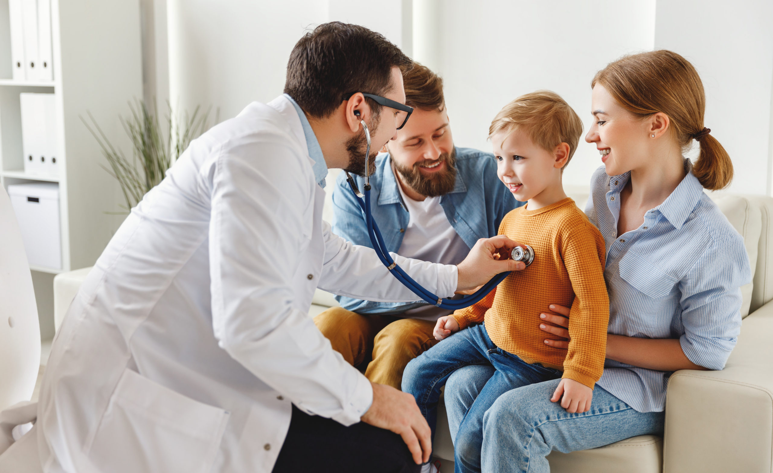 Doctor listening lungs of boy during family check up