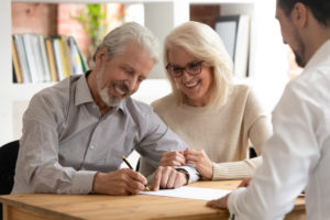 Happy older family couple happily signing a funeral insurance