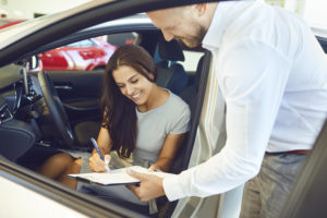 A young woman buys a car in a car showroom.