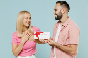 A smiling young couple giving a gift voucher as Christmas present