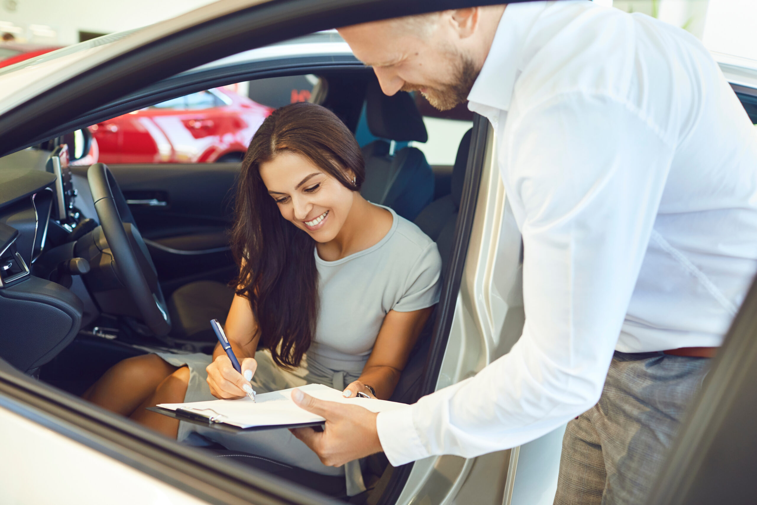 A young woman happily signing a car lease agreement