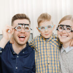 Cheerful family with small child reception doctor ophthalmologist using glasses