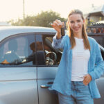 Happy woman showing keys to her new fuel efficient car