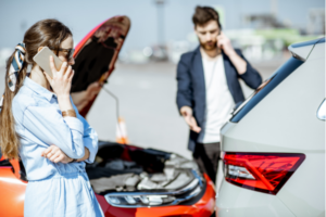 A man and woman calling their respective insurers after car accident