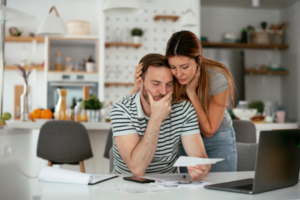 Concerned couple reviewing their finances together, looking worried and stressed.