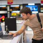 A man in a gadget shop considering a rent to buy laptop