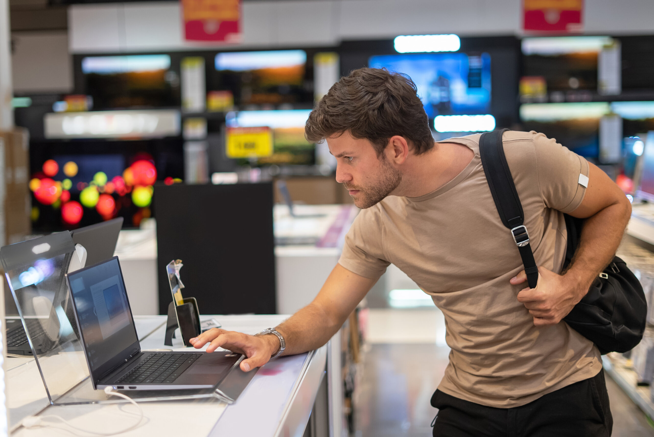 A man in a gadget shop considering a rent to buy laptop