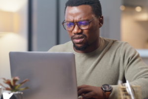 Shocked man reading fake reviews of a vacation rental on Booking.com on his laptop