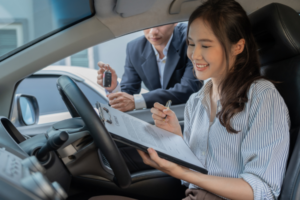 A smiling woman purchasing a secondhand car with remaining warranty