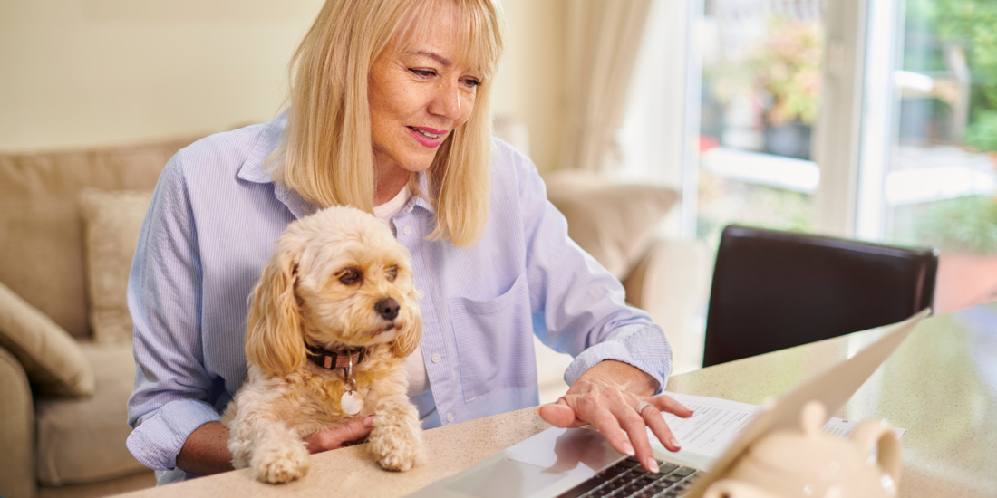 A woman completing a pet insurance claim form online with her dog