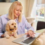 A woman completing a pet insurance claim form online with her dog