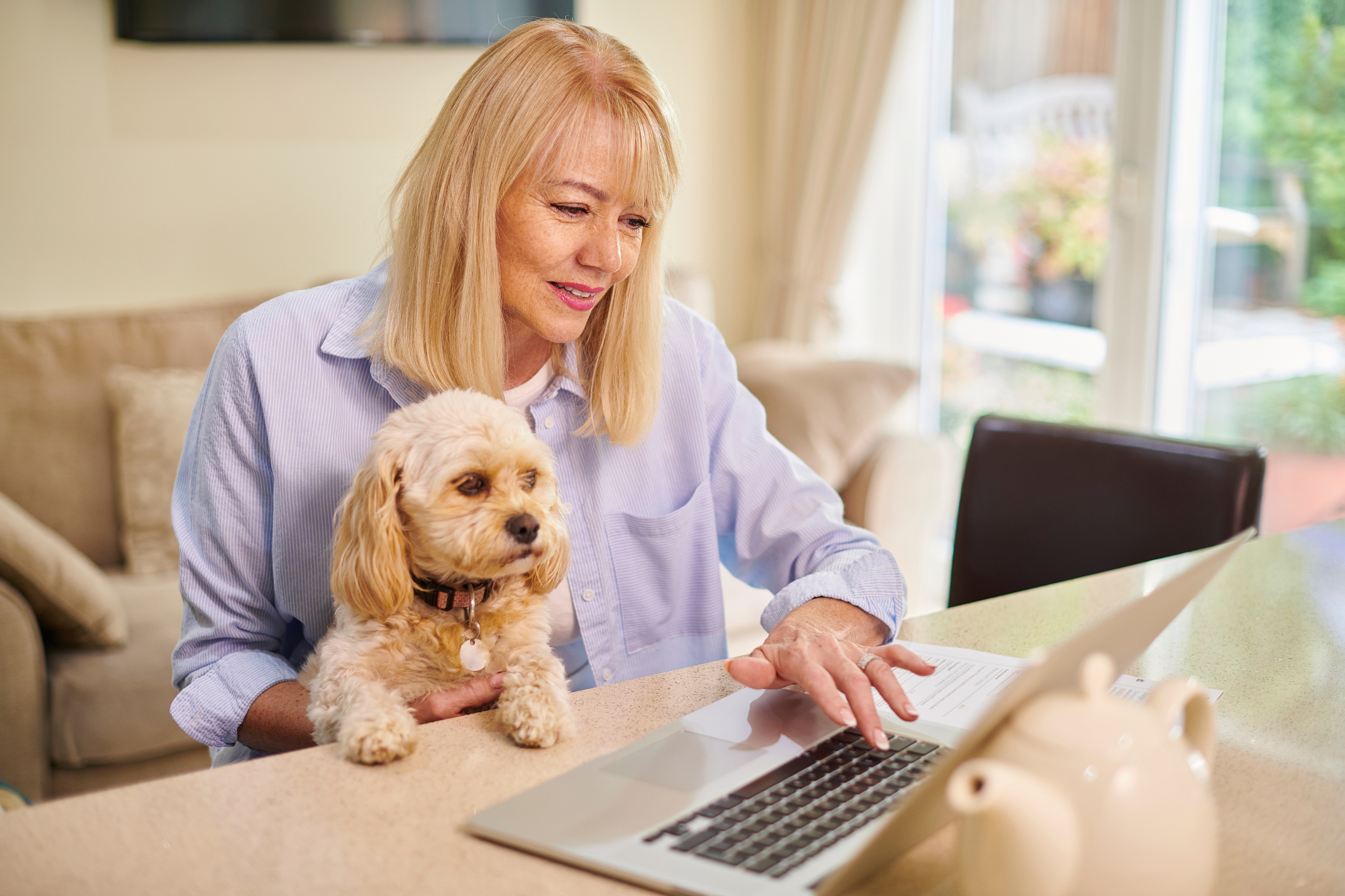 A woman completing a pet insurance claim form online with her dog