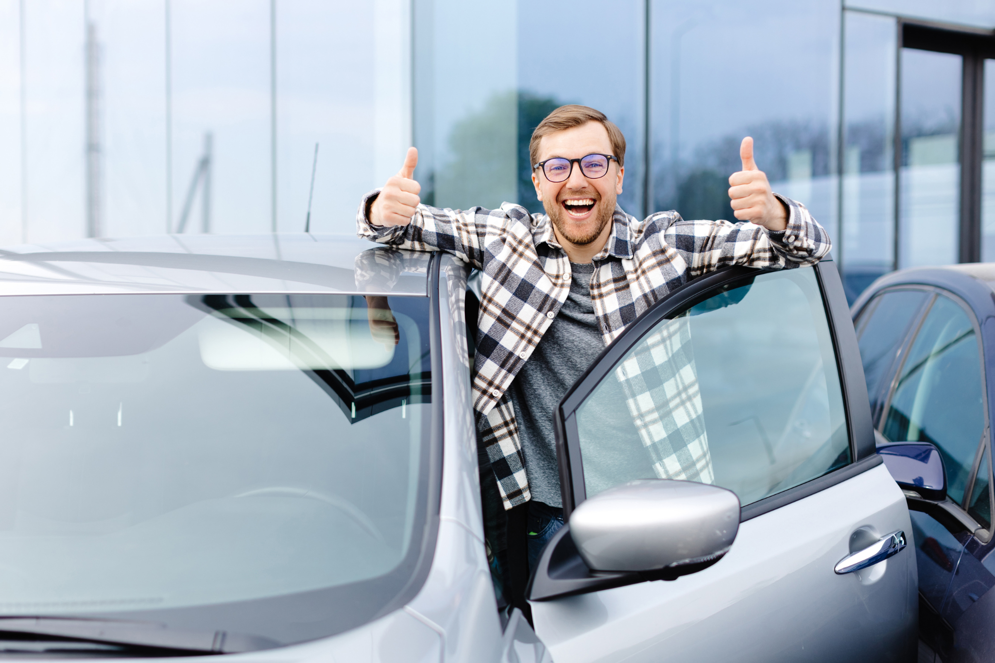 A happy man gesturing thumbs up buying used car in a car yard