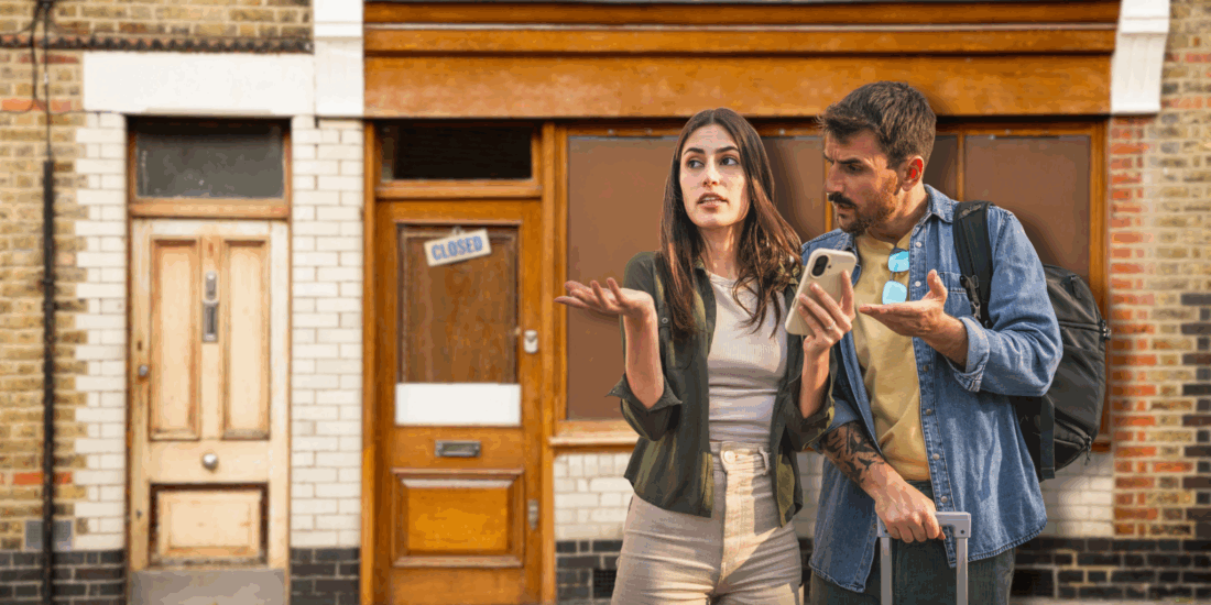 Confused couple outside a closed shop, realising they were scammed by a ghost store