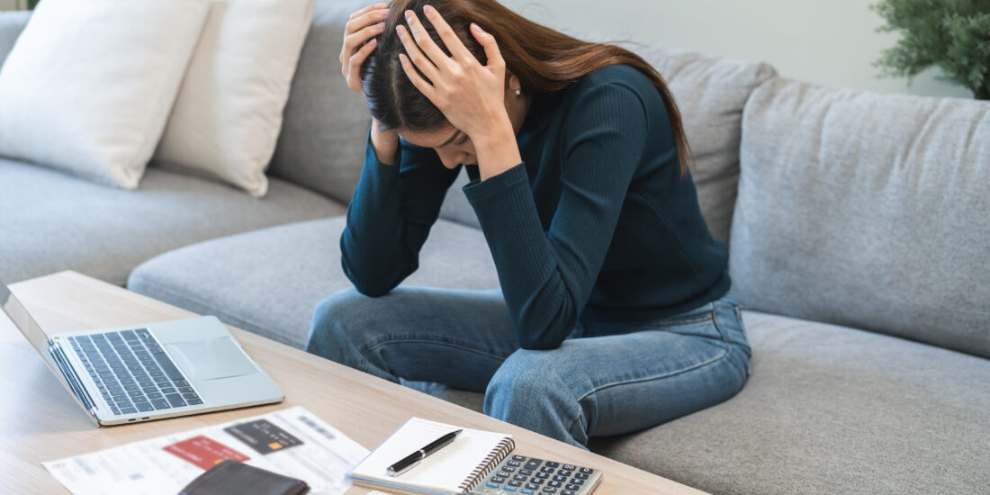 Woman sitting at home looking stressed while checking banking statements