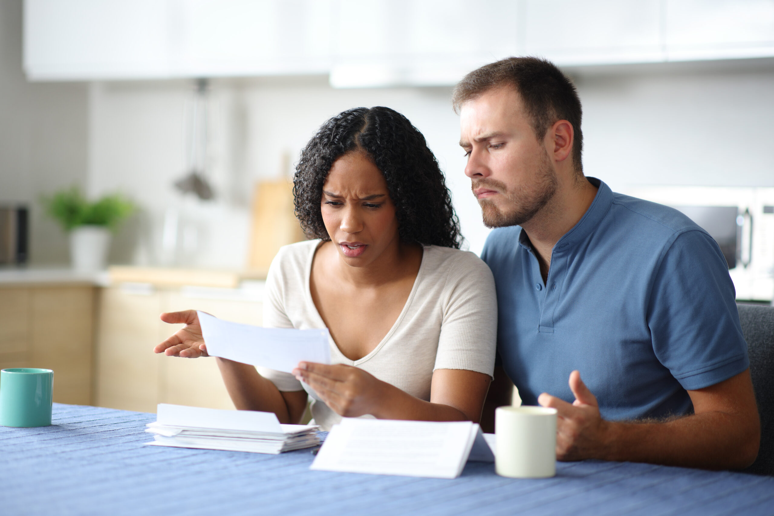 Frustrated couple reviewing unexpected transactions on a bank statement at home