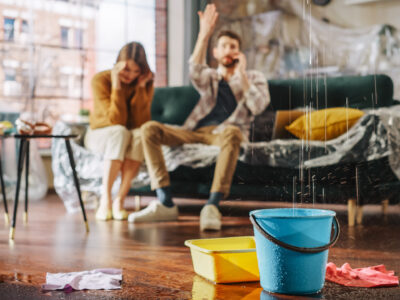Frustrated couple in their living room dealing with a faulty Iplex pipe and leaking roof