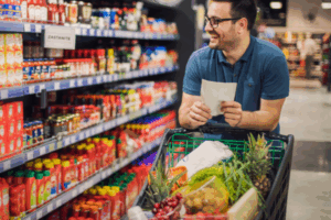 Man grocery shopping with a list, checking items and unit prices to stick to a budget