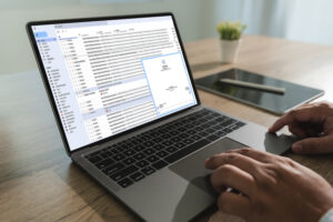 Close-up of a man typing on a laptop, drafting an email to file a banking complaint