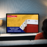 A woman watching a tv news report about the Robodebt class action settlement, showing a Federal Court building and a Royal Commission report on screen