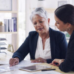 Older woman meeting with her lawyer to review documents and discuss her superannuation benefits for retirement