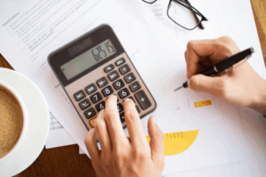 Close-up of hands using a calculator and signing documents related to superannuation contributions and retirement savings
