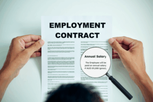 Papers showing employment contract with annual salary clause highlighted
