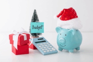Calculator and piggy bank on a table with a Christmas tree symbolising saving money for the holidays