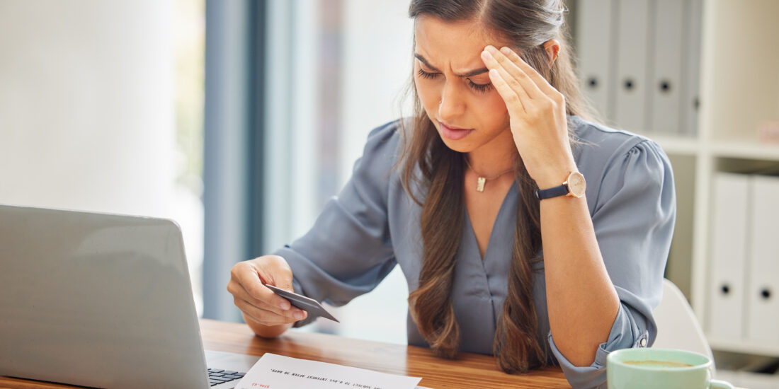 Woman looking stressed while checking a credit card invoice and BNPL charges, concerned about unexpected charges after the holidays.