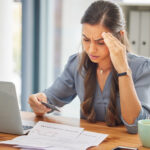 Woman looking stressed while checking a credit card invoice and BNPL charges, concerned about unexpected charges after the holidays.