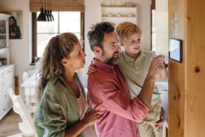 Family looking at smart thermostat, adjusting, lowering heating temperature at home. Concept of sustainable, efficient, and smart technology in home heating and thermostats.