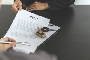 Close-up of a customer reviewing a car rental agreement about car rental damage claims before signing