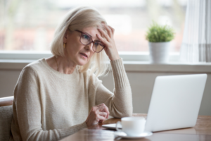Older woman sitting at a desk looking at a laptop, looking confused while going through an online form, highlighting renters data privacy concerns.