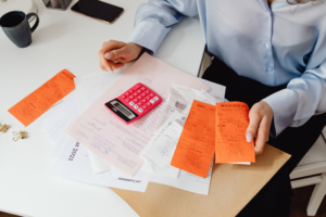 Hands collecting receipts and financial records beside a computer, preparing evidence for a telco outage compensation claim