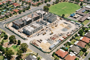 Aerial view of a large data centre under construction beside a primary school and surrounded by Australian homes