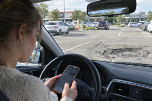 Woman using herphone to find out who is responsible for a pothole in a shopping centre car park